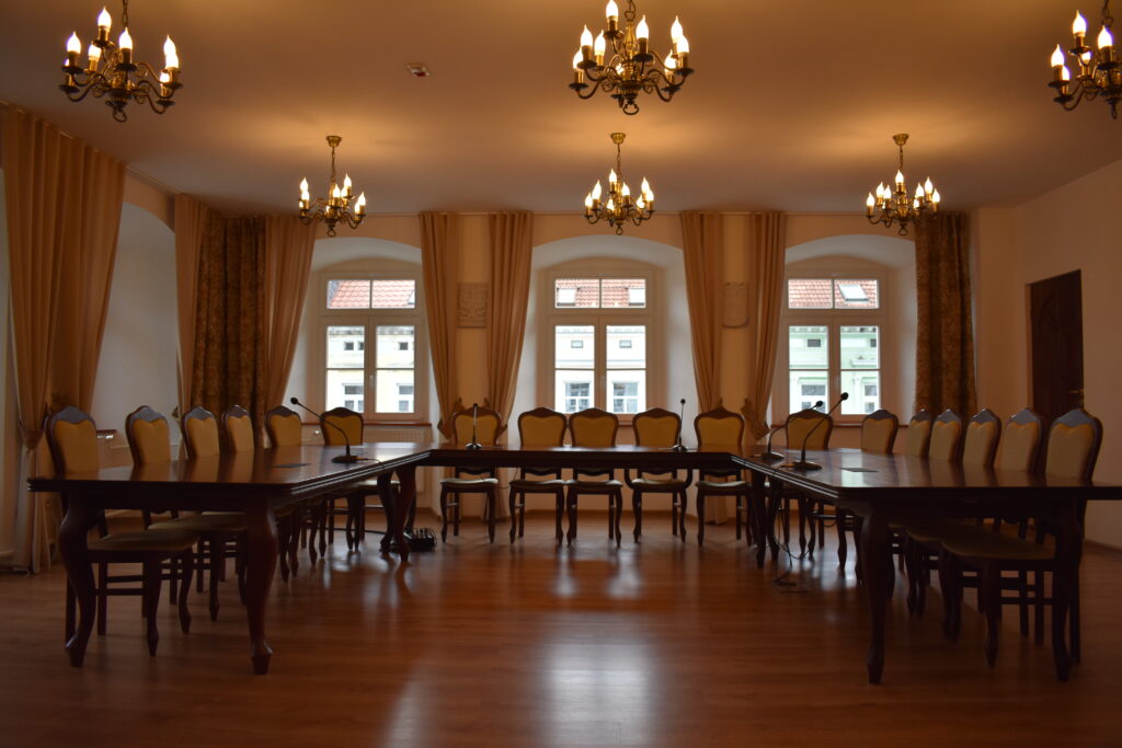 Sala Rajców Urzędu Miejskiego w Leśnej z dużym stołem konferencyjnym i krzesłami.